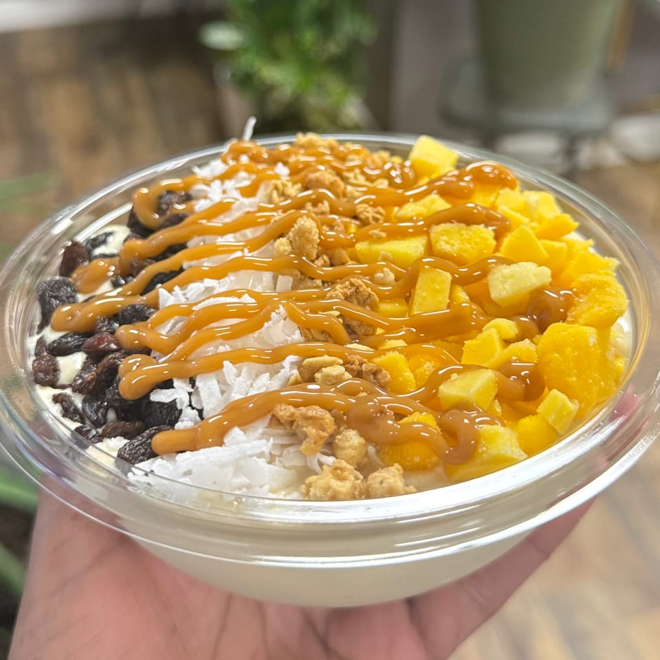 A healthy bowl from Smart Choice Nutrition 252 with mango, coconut, raisins, and caramel drizzle.