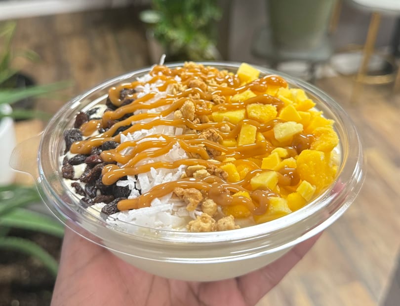 A healthy bowl from Smart Choice Nutrition 252 with mango, coconut, raisins, and caramel drizzle.